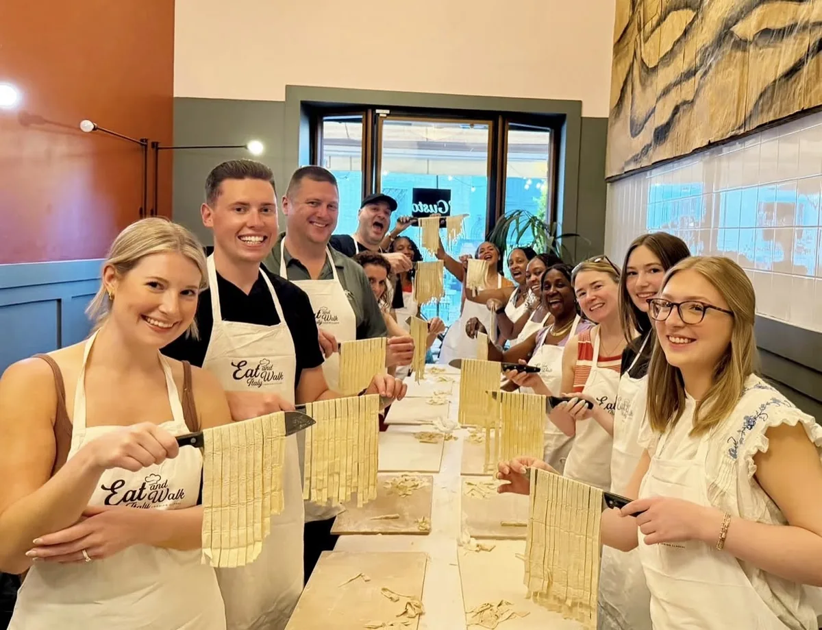 Guests holding fresh fettuccine made during a cooking class in Rome